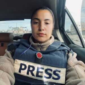 Bisan Owda sitting in a car wearing a PRESS vest